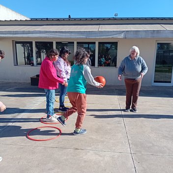 Concurrentes de Espacio Encuentro en una actividad física con pelota y aros en el patio